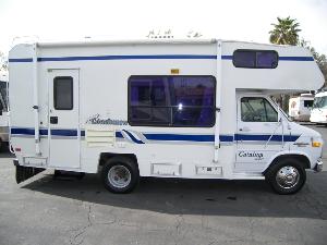 White RV with brand new blue stripe decals on a parking lot.