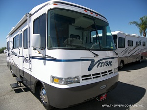 White Vision RV with brand new blue stripe decal painted on in the middle of a parking lot.