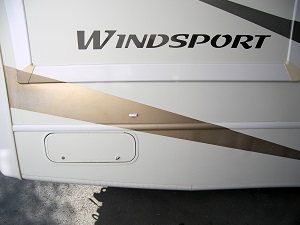 Close-up of a white Windsport RV with a newly painted gold stripe decal.