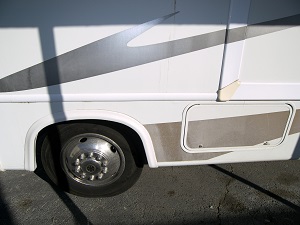 Close-up of bottom of white RV with faded black and brown decals.