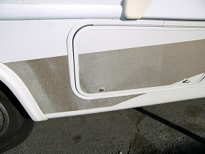 Close-up of a white RV with a faded brown decal next to a tire.